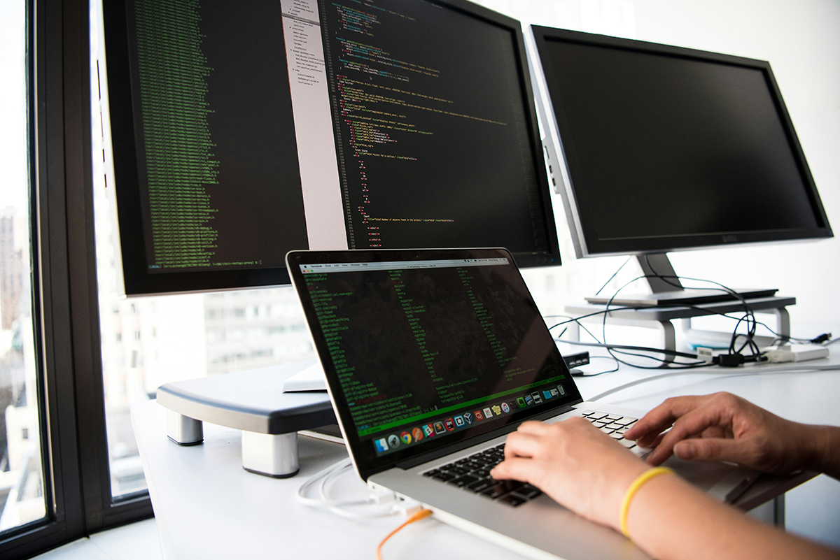 Hände auf Laptop mit Code auf dem Bildschirm