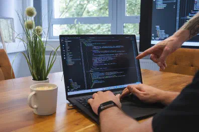 Hands typing on a laptop showing code