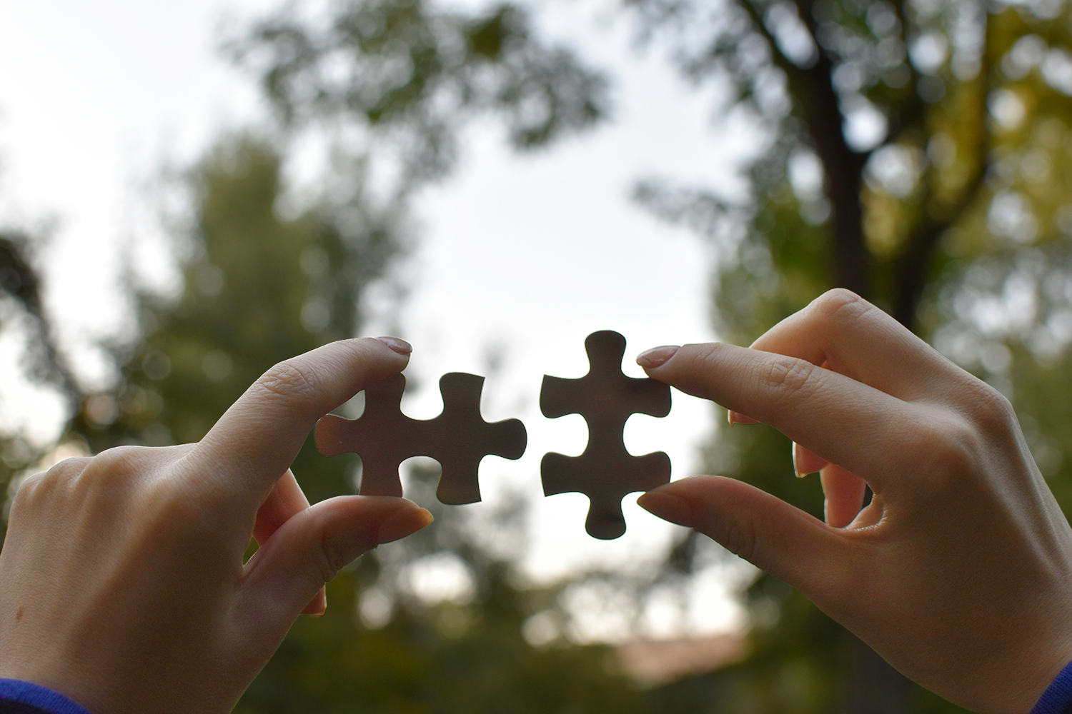 Zwei Hände fügen Puzzleteile zusammen